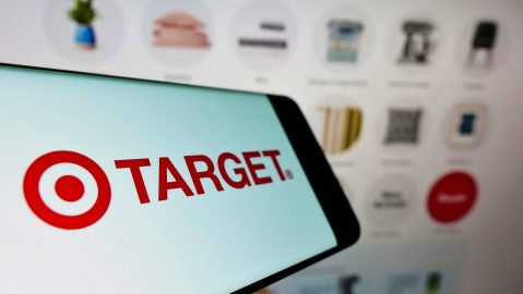 Teléfono móvil con el logotipo de la empresa minorista estadounidense Target Corporation en la pantalla frente al sitio web de la empresa.