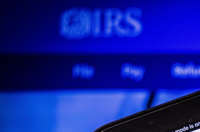 Hombre sostiene un teléfono inteligente con el Sitio web del IRS en la pantalla.