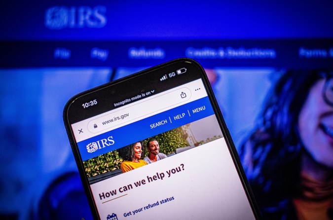 Hombre sostiene un teléfono inteligente con el Sitio web del IRS en la pantalla.