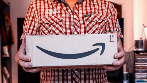 Un hombre sostiene una caja de cartón de Amazon.