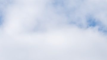 Un cartel en un poste de un restaurante Wendy's con un cielo azul de fondo.
