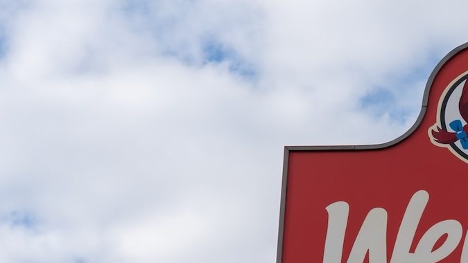 Un cartel en un poste de un restaurante Wendy's con un cielo azul de fondo.