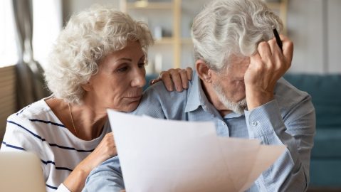 Un marido y una mujer maduros y angustiados de 60 años se sientan a la resolver su medicare.