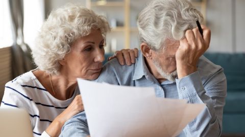 Un marido y una mujer maduros y angustiados de 60 años se sientan a la resolver su medicare.