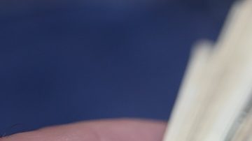 Un hombre sostiene billetes de un dólar. Fondo azul.