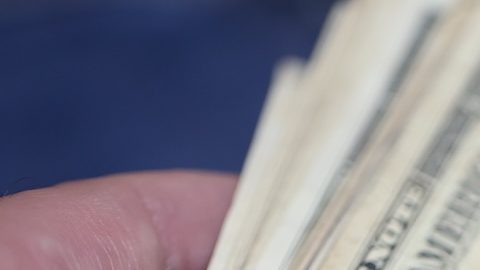 Un hombre sostiene billetes de un dólar. Fondo azul.