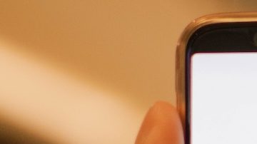 Mano sosteniendo un teléfono inteligente que muestra la aplicación Target con un centro comercial de fondo.