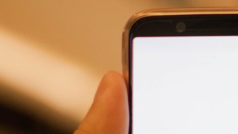 Mano sosteniendo un teléfono inteligente que muestra la aplicación Target con un centro comercial de fondo.