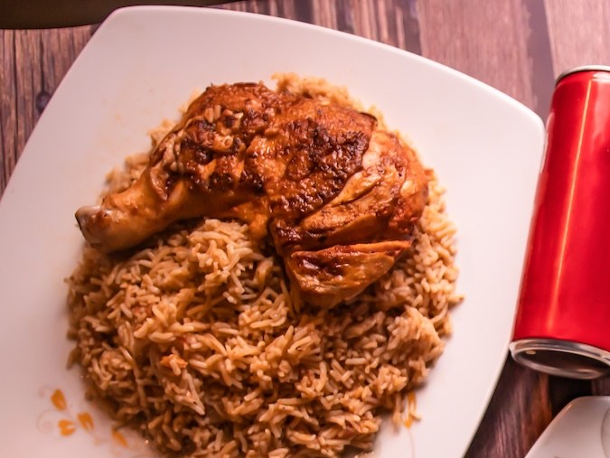 Mesa de comida rápida variada: seekh kabab y tikka biryani, arroz frito, pollo frito, shawarma seekh kabab, bebida, papas fritas, raita y ensalada, vista superior de la mesa de madera.