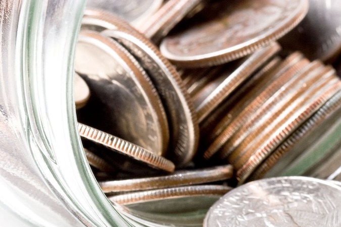 Monedas de cambio de 25 centavos en un frasco de vidrio aislado.