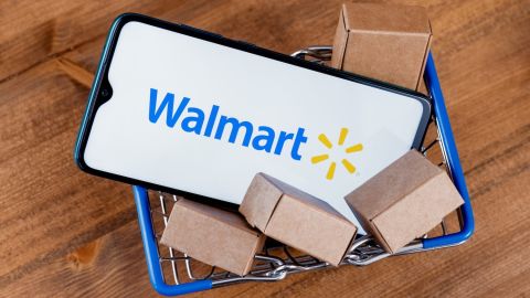 Teléfono inteligente con el logotipo de Walmart en la pantalla y paquetes en el carrito de compras.