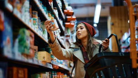 Mujer joven comprando comida enlatada en una tienda de comestibles.