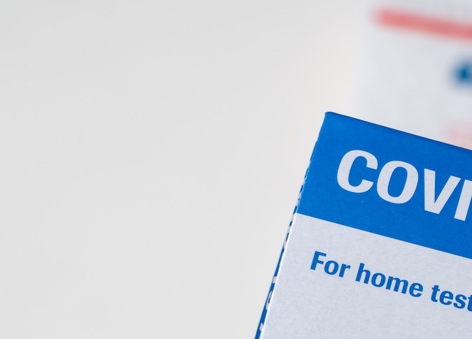 Un hombre mayor abre la prueba casera suministrada por el gobierno federal para detectar la COVID-19 con un sobre del servicio postal de EE. UU.