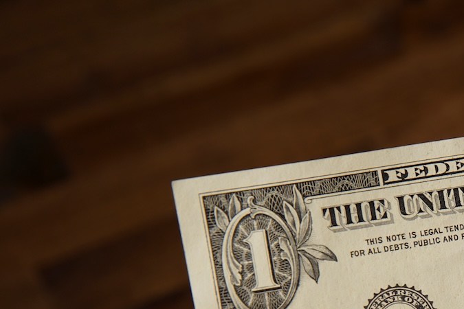 Mano de un hombre tiene un billete de $1 dólar.