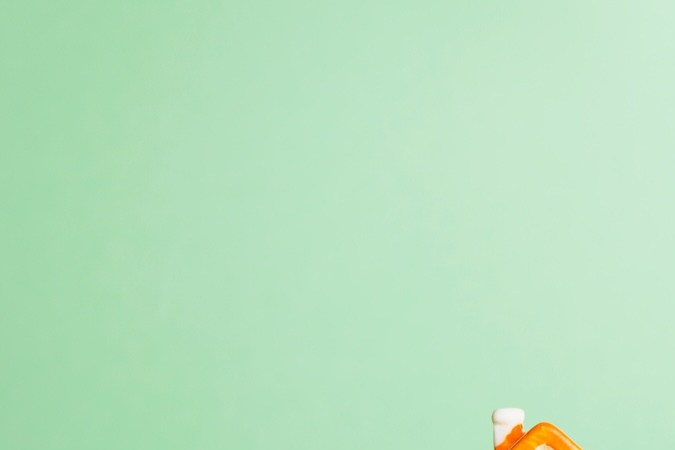 Casas miniatura de cerámica sobre pilas de monedas.