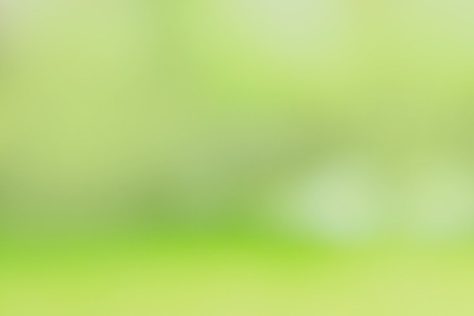 Una pareja en miniatura se encuentra entre una pila de monedas y una pequeña casa sobre un fondo de jardín verde borroso.