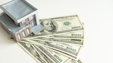 Casa miniatura sobre billetes de $100 dólares.