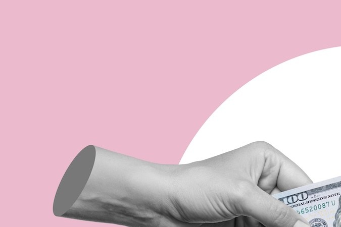 Mano femenina que sostiene un billete de cien dólares en efectivo y se lo pasa a otra persona sobre un fondo rosa.