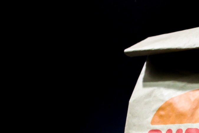 Embalaje de bolsas de papel marrón Burger King sobre fondo negro.