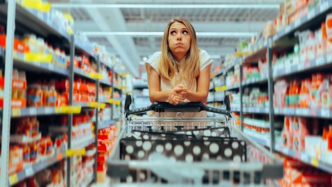 Mujer abrumada en un pasillo del supermercado.