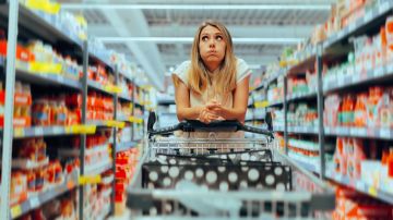 Mujer abrumada en un pasillo del supermercado.