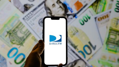 Aplicación de DirecTV en un teléfono inteligente sobre billetes de $100 dólares.