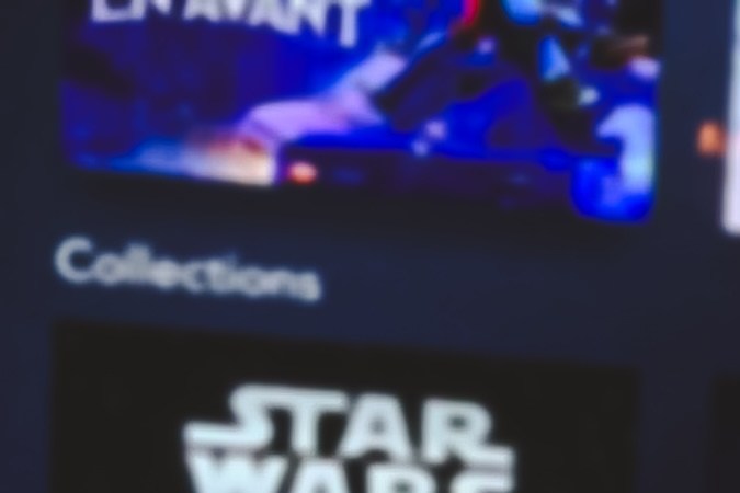 Hombre con control remoto de TV en mano y logo de Disney plus de fondo.