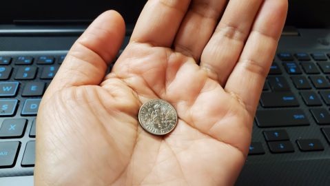 Mano levantando una moneda de diez centavos sobre un fondo de teclado de computadora. Concepto de negocio online para ganar dinero.