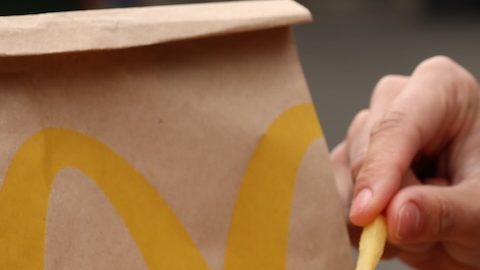 Mujer con menú de McDonald's en una mesa de madera al aire libre, primer plano.