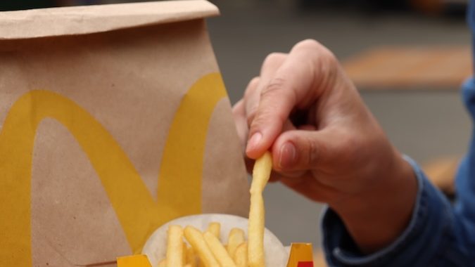 Mujer con menú de McDonald's en una mesa de madera al aire libre, primer plano.