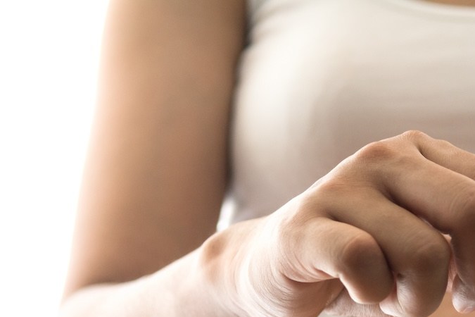 Mujer embarazada joven que deja caer una moneda de oro en el vaso de una alcancía para ahorrarle dinero a su bebé recién nacido aislado sobre fondo blanco.