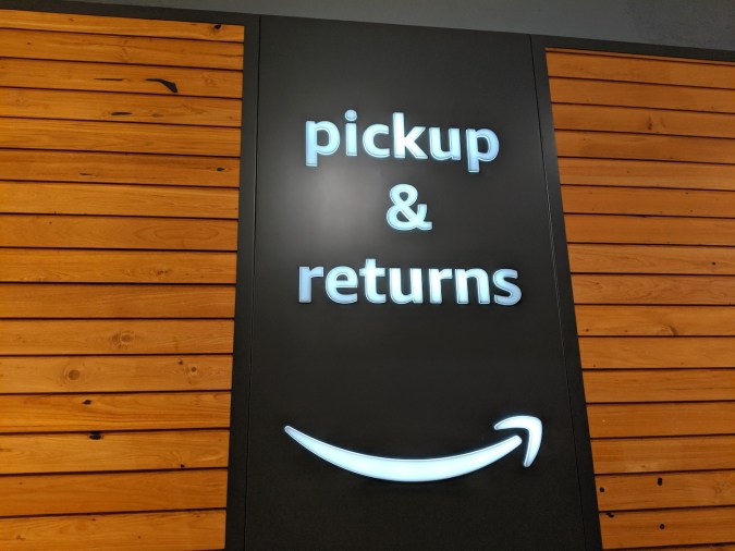 Recogida y devolución de libros en tienda de Amazon. Cartel de sonrisa por la noche.