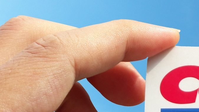 Mano sosteniendo una membresía de Costco frente al cielo azul.