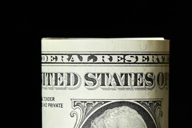 Billete de un dólar enrollado sobre un fondo de pilas de monedas