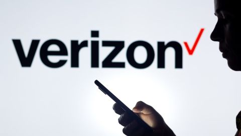 En esta ilustración fotográfica, la silueta de una mujer sostiene un teléfono inteligente con el logotipo de Verizon Communications de fondo.