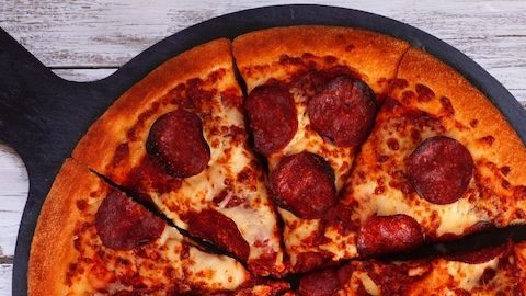 Mesa de comida con temática de fútbol o Super Bowl. Pizza, hamburguesas, alitas, bocadillos y guarniciones.