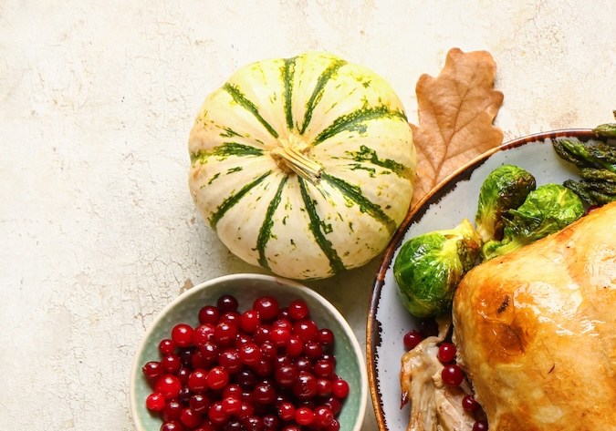 Delicioso pavo al horno y diferentes comidas para el Día de Acción de Gracias sobre fondo claro.