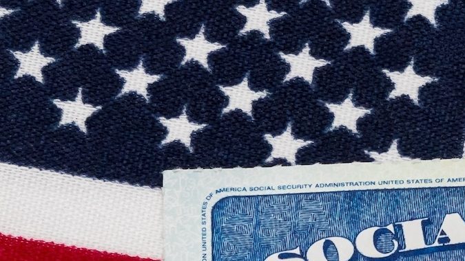 Tarjeta de seguridad social, billete de 100 dólares y bandera estadounidense. Concepto de pago de prestaciones de seguridad social, jubilación y prestaciones del gobierno federal.