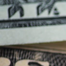 Primer plano de moneda estadounidense: moneda de un centavo y billetes de dólar sobre superficie de madera.