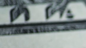 Primer plano de moneda estadounidense: moneda de un centavo y billetes de dólar sobre superficie de madera.