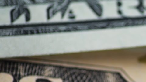 Primer plano de moneda estadounidense: moneda de un centavo y billetes de dólar sobre superficie de madera.