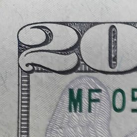 Primer plano de una moneda de cuarto de dólar encima de un billete de 10 y 20.