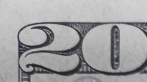 Primer plano de una moneda de cuarto de dólar encima de un billete de 10 y 20.