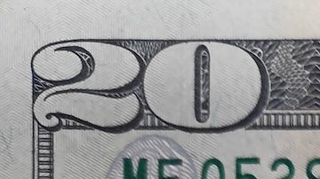 Primer plano de una moneda de cuarto de dólar encima de un billete de 10 y 20.