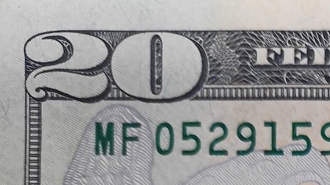 Primer plano de una moneda de cuarto de dólar encima de un billete de 10 y 20.