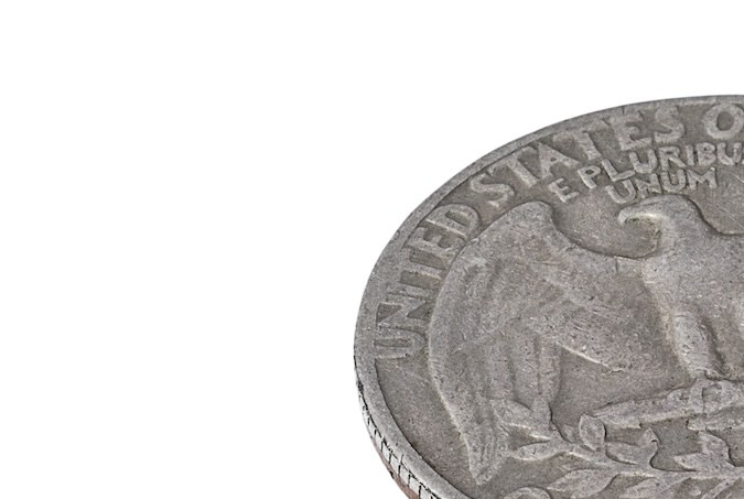 Pila de monedas de un cuarto de dólar sobre fondo blanco.