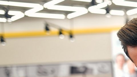 Un hombre toca con delicadeza y sonrisa un televisor de plasma en una tienda de electrodomésticos, aparatos electrónicos y gadgets. Compra de un televisor nuevo, día de rebajas.