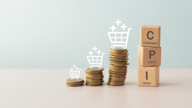 Concepto de IPC, índice de precios al consumidor. Bloque de madera con la palabra IPC y pila de monedas e icono de carrito de compras.