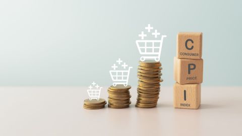 Concepto de IPC, índice de precios al consumidor. Bloque de madera con la palabra IPC y pila de monedas e icono de carrito de compras.