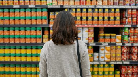 Mujer, comestibles y alimentos enlatados en supermercado para ahorrar dinero, comprar y productos para la nutrición.